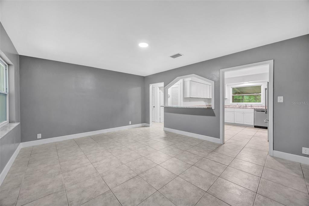 A living room with gray walls, tile flooring, and a pass-through window to the kitchen — 308 S KINGSWAY ROAD, SEFFNER, FL
