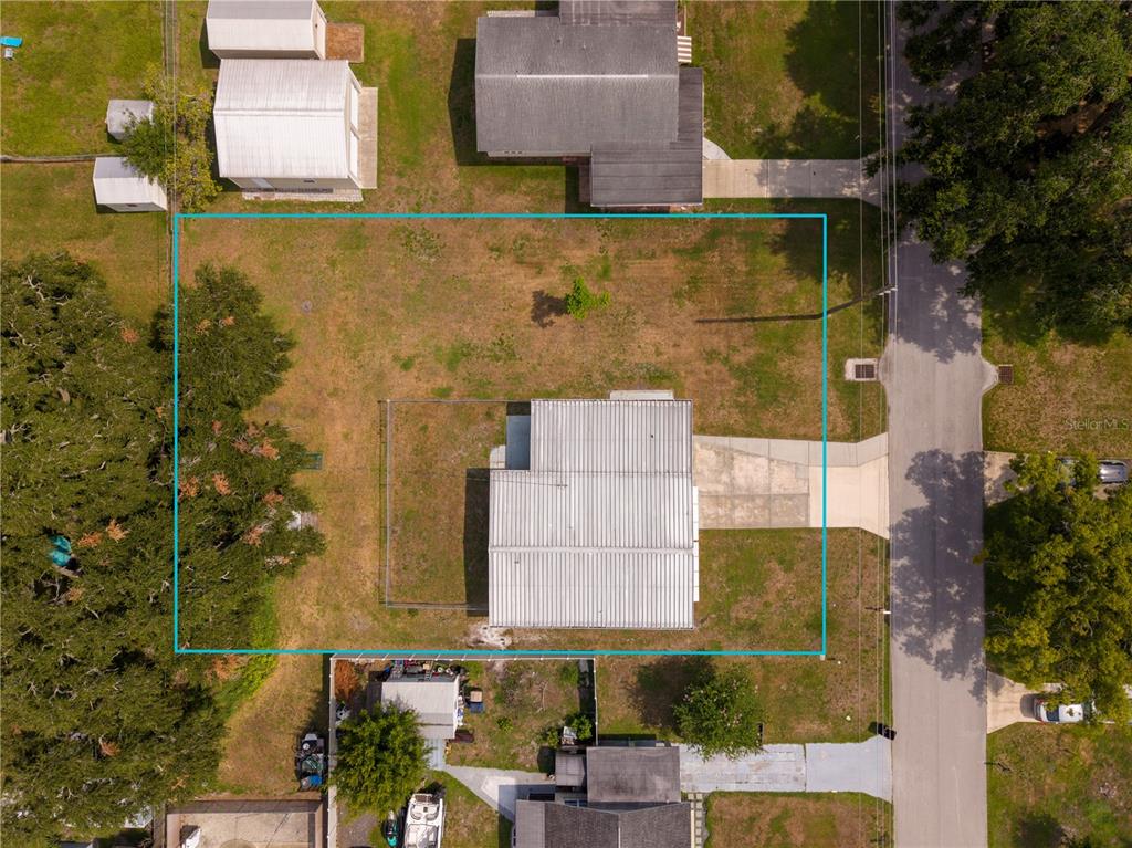 An aerial view shows a house with a metal roof on a fenced residential lot — 332 ILLINOIS AVENUE, ST CLOUD, FL