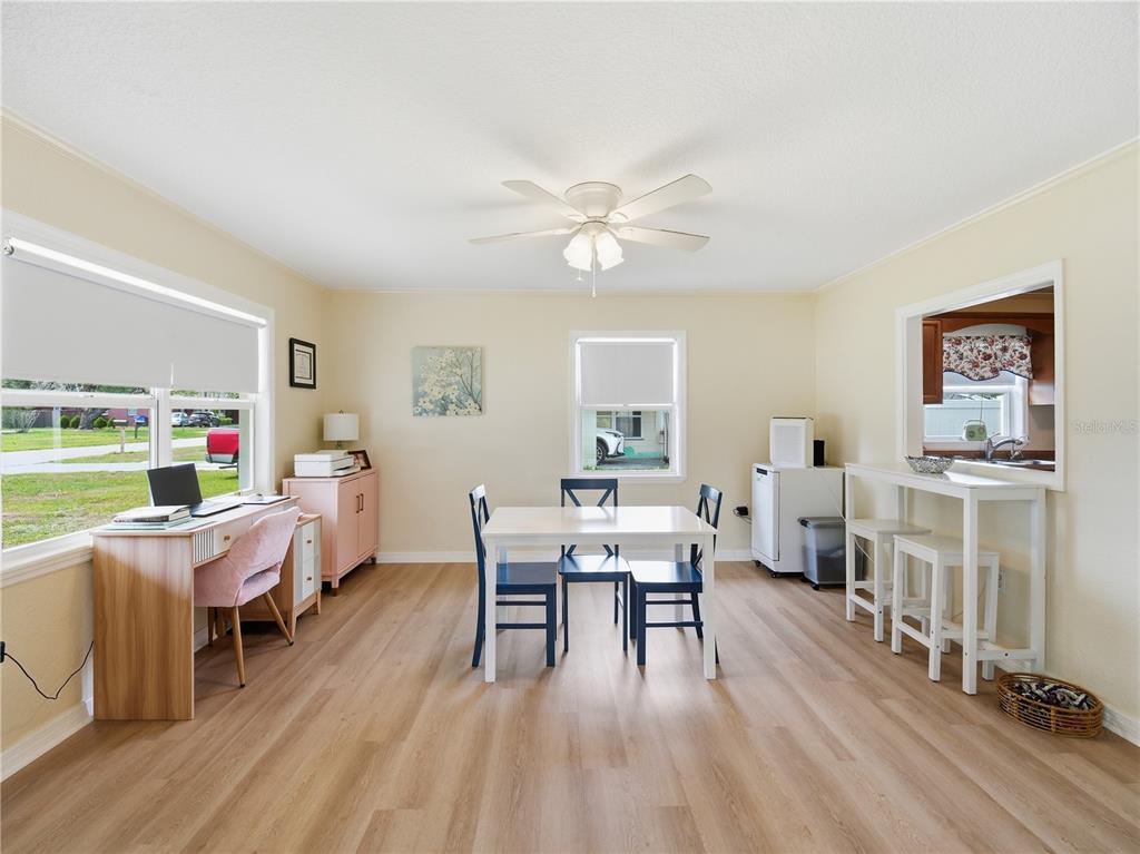 A dining room with light wood flooring, a central table, and a built-in desk area — 332 ILLINOIS AVENUE, ST CLOUD, FL