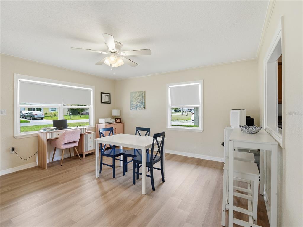 A dining room with light wood floors, a white table, dark chairs, and a desk — 332 ILLINOIS AVENUE, ST CLOUD, FL