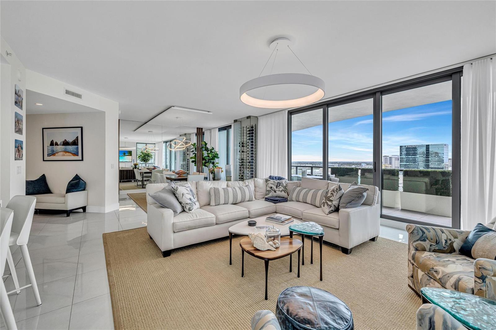 A modern living room features a white sectional sofa, nested coffee tables, and floor-to-ceiling windows — 100 E Las Olas Boulevard # 1701, Fort Lauderdale FL 33301, FORT LAUDERDALE, FL