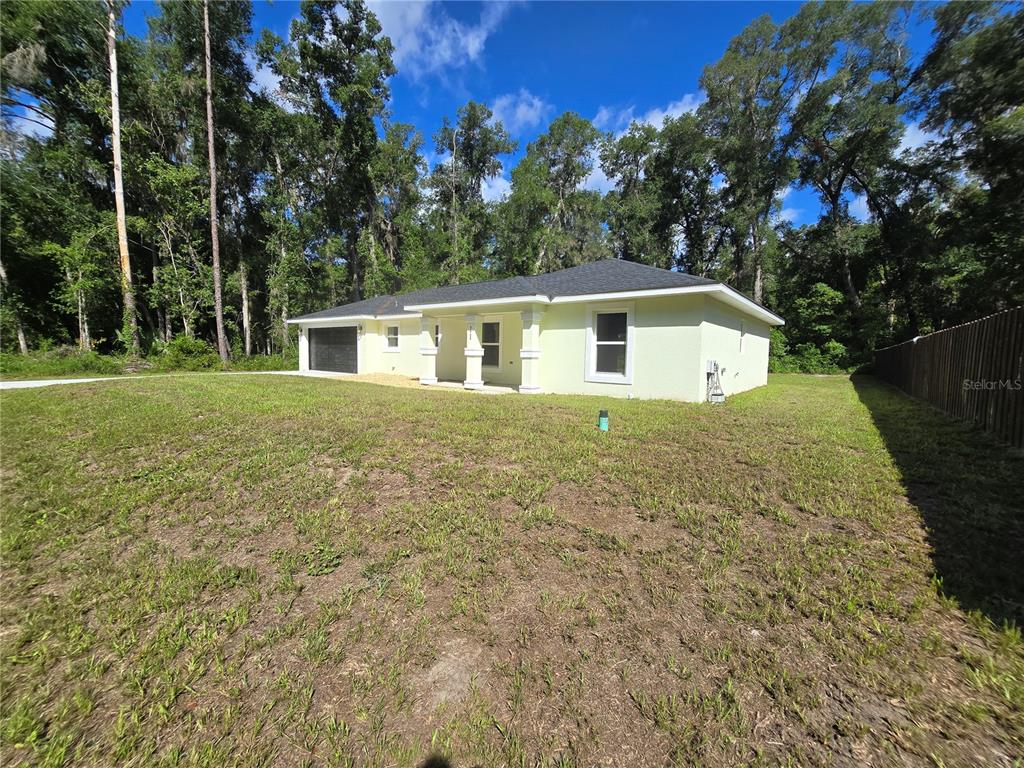 A light yellow single-story house with a dark roof sits on a grassy lot — 11 SEQUOIA LOOP PLACE, OCKLAWAHA, FL