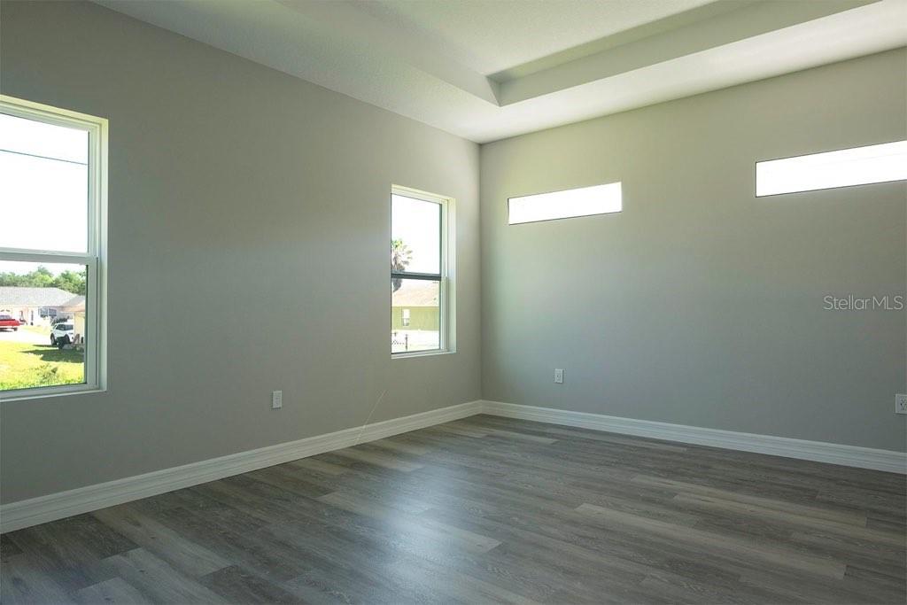 An empty room with gray walls, wood-look flooring, and several windows — 2028 SW 153 LOOP, OCALA, FL