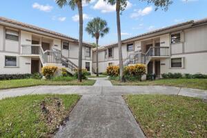 A two-story apartment building with beige siding, exterior staircases, and a central palm tree — 3130 Millwood Terrace # 2110, Boca Raton FL 33431, BOCA RATON, FL