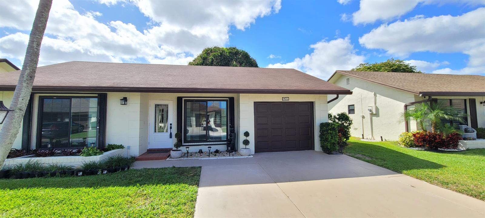 A single-story house with a brown roof, white walls, and a dark brown garage door — 6209 Olivewood Circle, FL 33463, FL