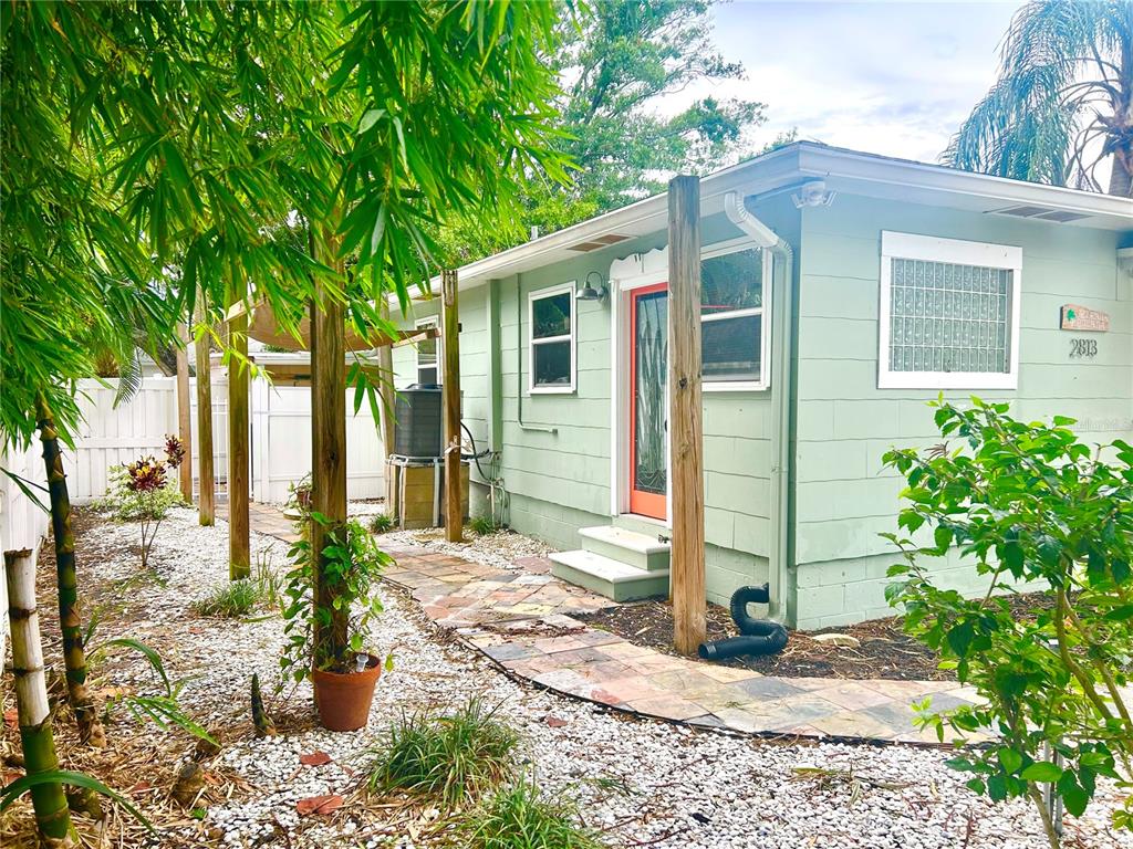 A light green house exterior features a stone walkway, a red door, and bamboo landscaping — 2813 46TH STREET S, GULFPORT, FL