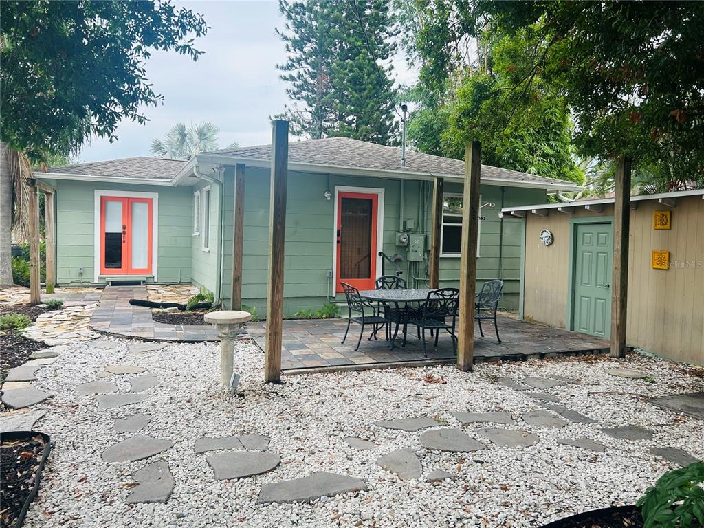 The exterior of a green house features orange doors, a stone patio, and gravel landscaping — 2813 46TH STREET S, GULFPORT, FL