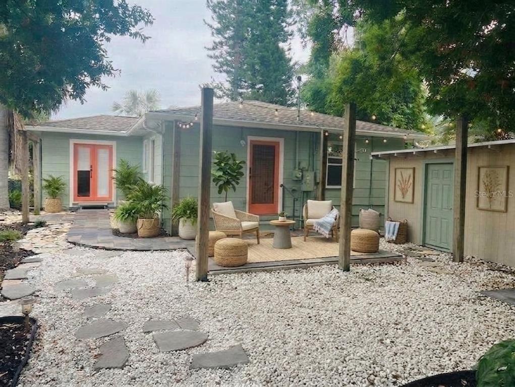 A backyard patio features a gravel ground, stone path, and a wooden deck with seating — 2813 46TH STREET S, GULFPORT, FL