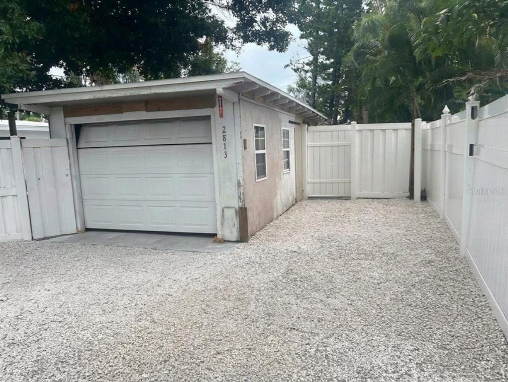 A detached garage with a white door and siding sits on a gravel driveway — 2813 46TH STREET S, GULFPORT, FL