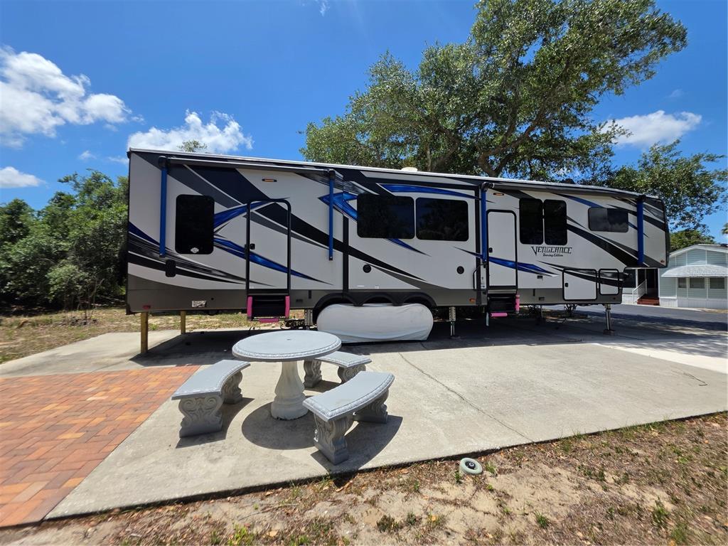 A Vengeance toy hauler RV is parked on a concrete pad with a stone table — 7371 INTERNATIONAL CIRCLE, LAKE WALES, FL