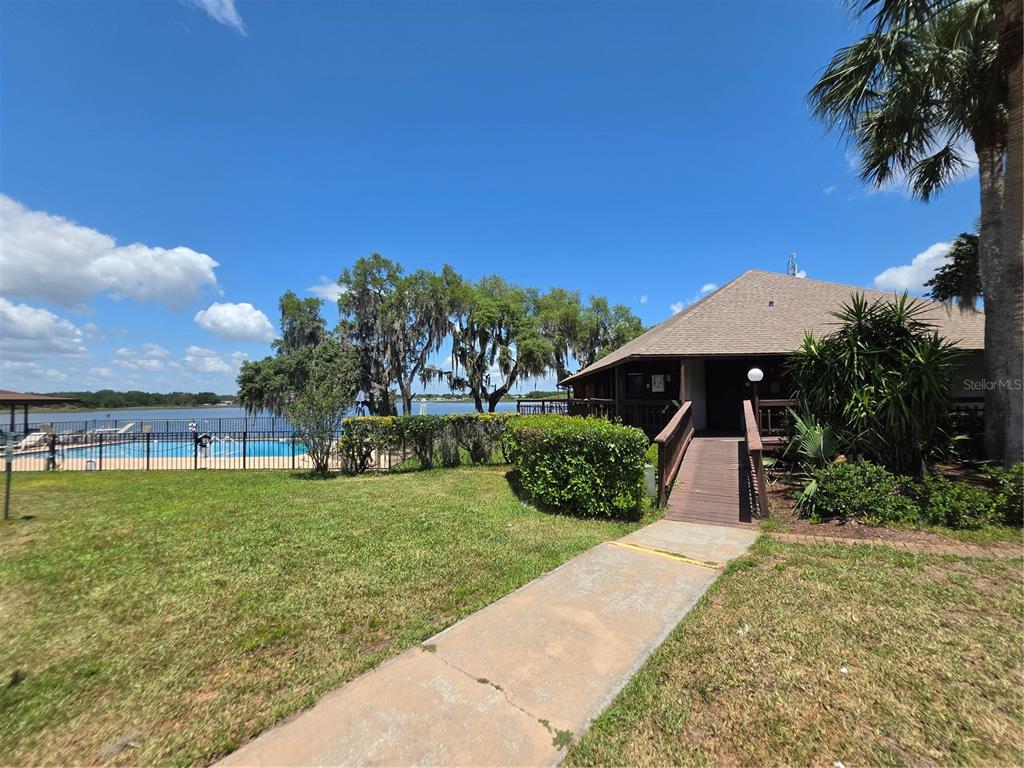 A concrete walkway leads to a building entrance next to a fenced outdoor swimming pool — 7371 INTERNATIONAL CIRCLE, LAKE WALES, FL