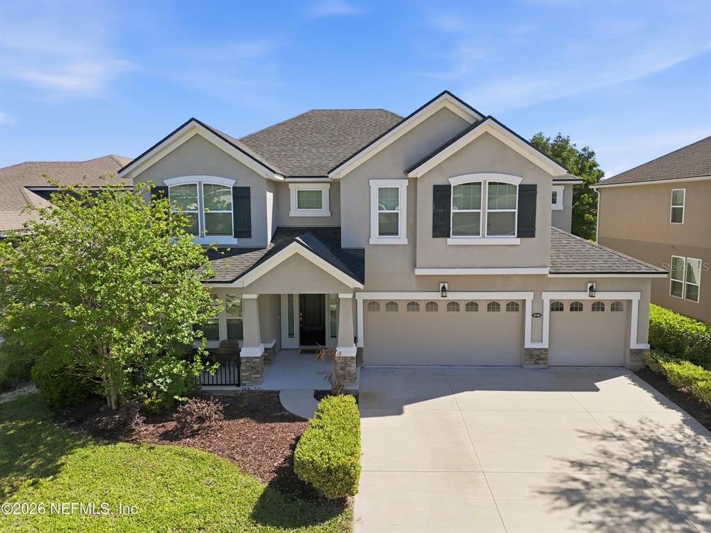 A two-story suburban house with a beige stucco exterior, a three-car garage, and landscaping — 6946 AZALEA GROVE DRIVE, JACKSONVILLE, FL