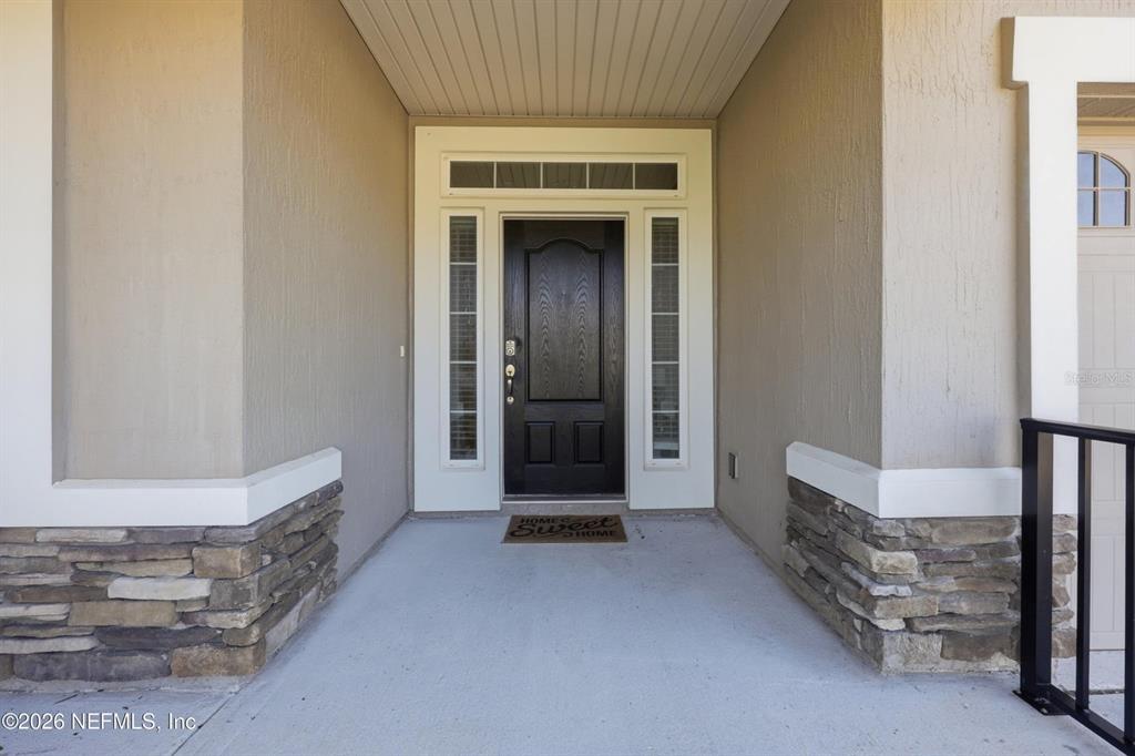 The front entrance features a dark door with sidelights and stone veneer accents — 6946 AZALEA GROVE DRIVE, JACKSONVILLE, FL