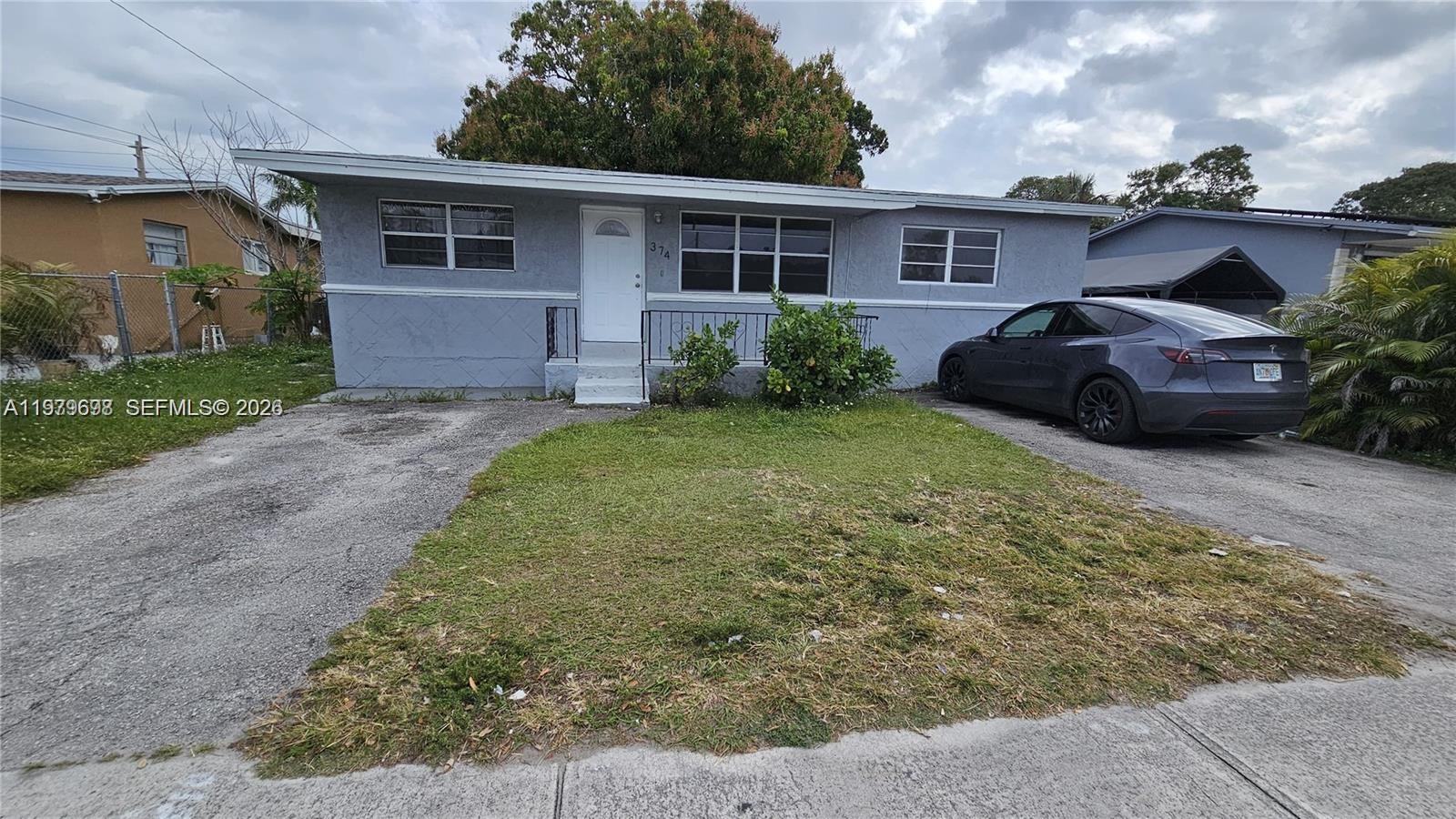 A single-story gray house with a front lawn and a parked car in the driveway — 374 NW 31st Ave, Pompano Beach FL 33311, POMPANO BEACH, FL