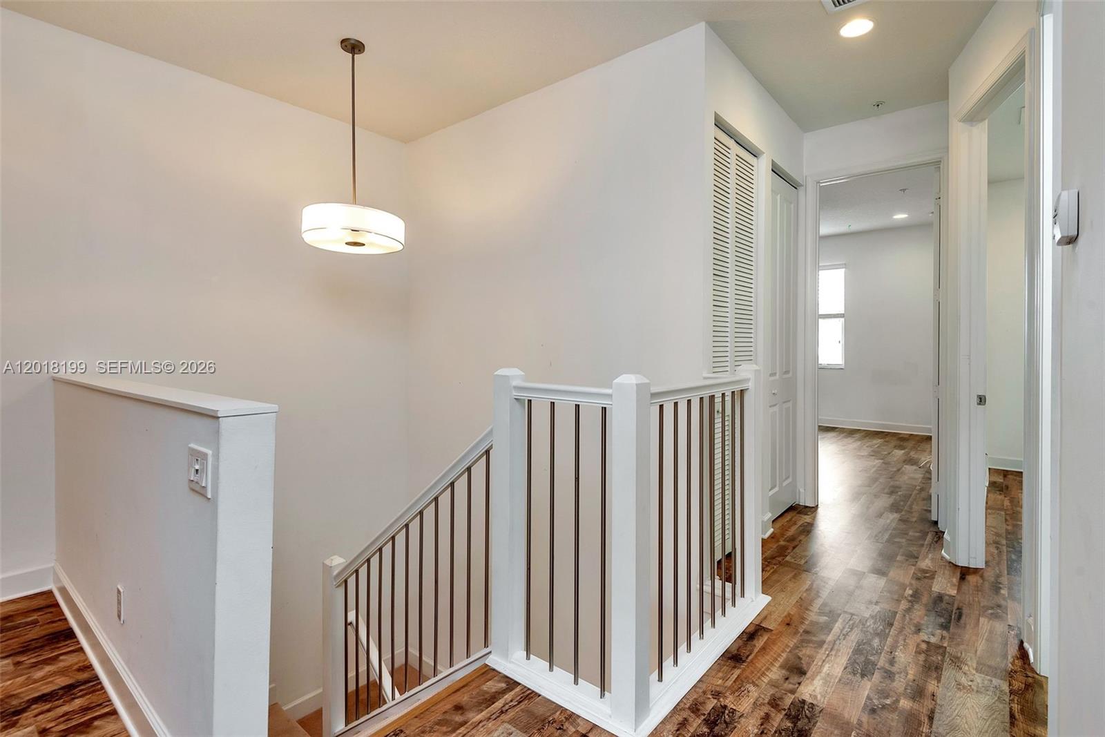 A staircase with white railings and a pendant light leads to a hallway with flooring — 22954 Clear Echo Dr # 29, Boca Raton FL 33433, BOCA RATON, FL