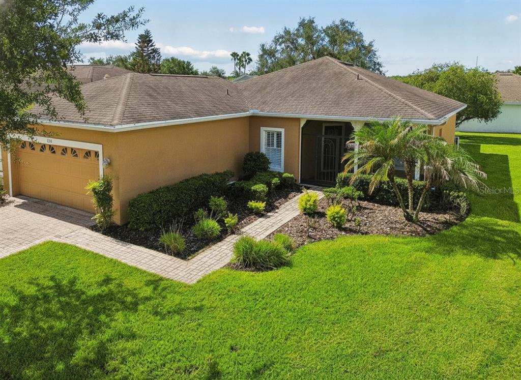 An exterior view of a tan, single-story house with a two-car garage and landscaped yard — 230 BAY DRIVE, KISSIMMEE, FL