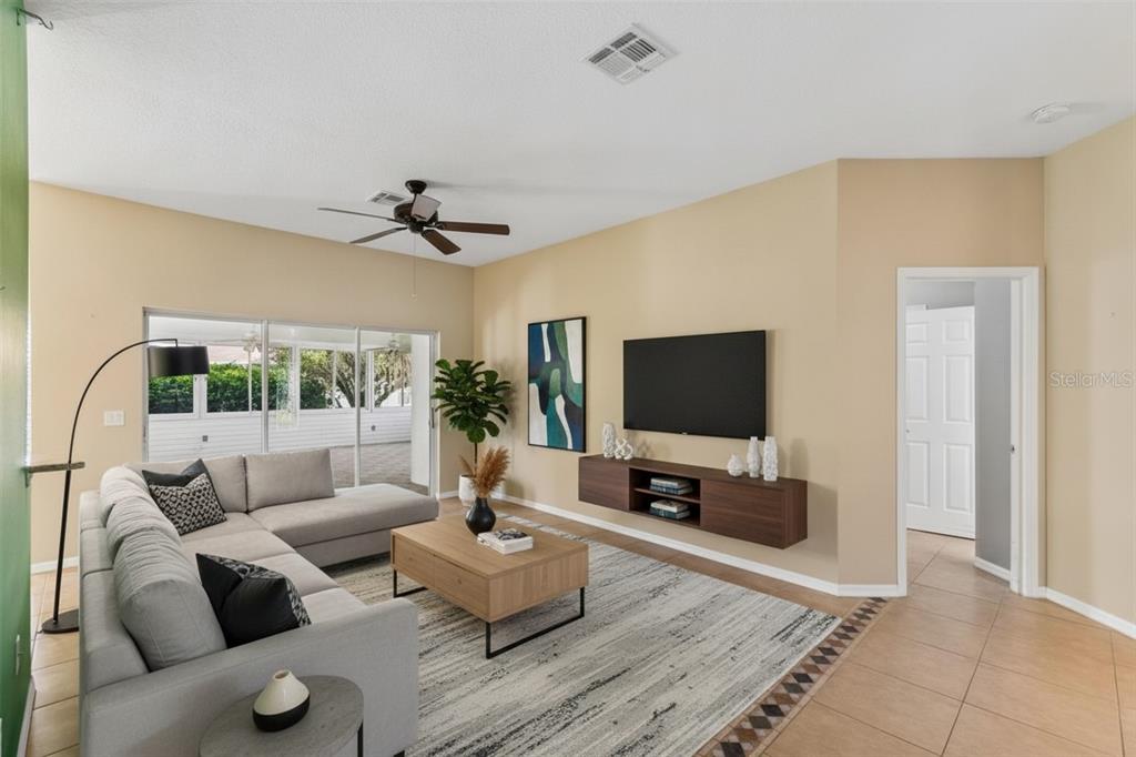 A living room features a grey sectional sofa, a wall-mounted media console, and a sliding door — 230 BAY DRIVE, KISSIMMEE, FL