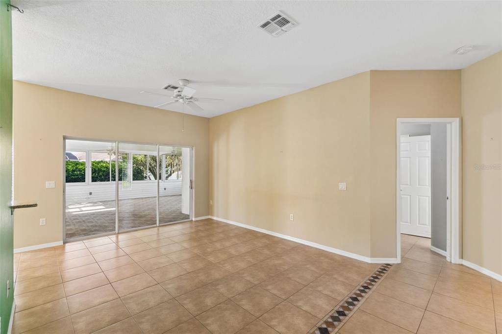 A living room with beige walls, tile flooring, a ceiling fan, and sliding glass doors — 230 BAY DRIVE, KISSIMMEE, FL