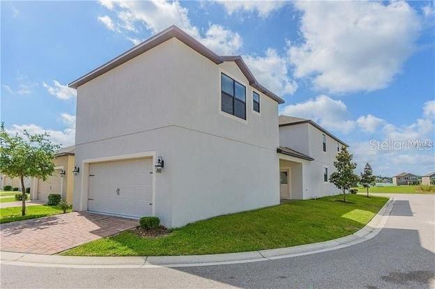 A two-story house with a light-colored stucco exterior and a two-car garage — 13303 PENSHURST LANE, WINDERMERE, FL