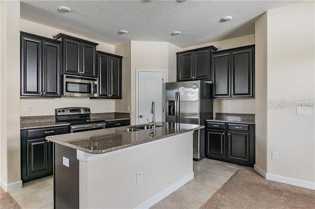 A kitchen features dark wood cabinets, granite countertops, stainless steel appliances, and a central island — 13303 PENSHURST LANE, WINDERMERE, FL