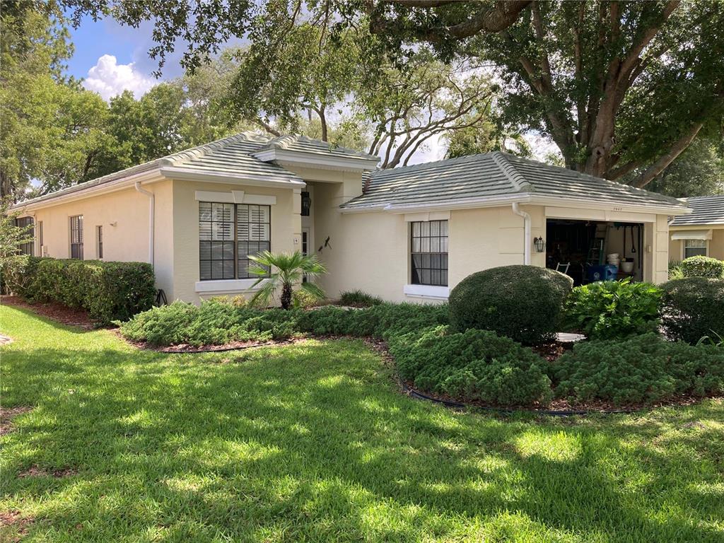 A single-story house with a light-colored stucco exterior, a tiled roof, and landscaped front yard — 9029 PENELOPE DRIVE, WEEKI WACHEE, FL