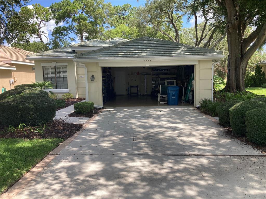A single-story house with a beige stucco exterior, a tile roof, and an open garage — 9029 PENELOPE DRIVE, WEEKI WACHEE, FL
