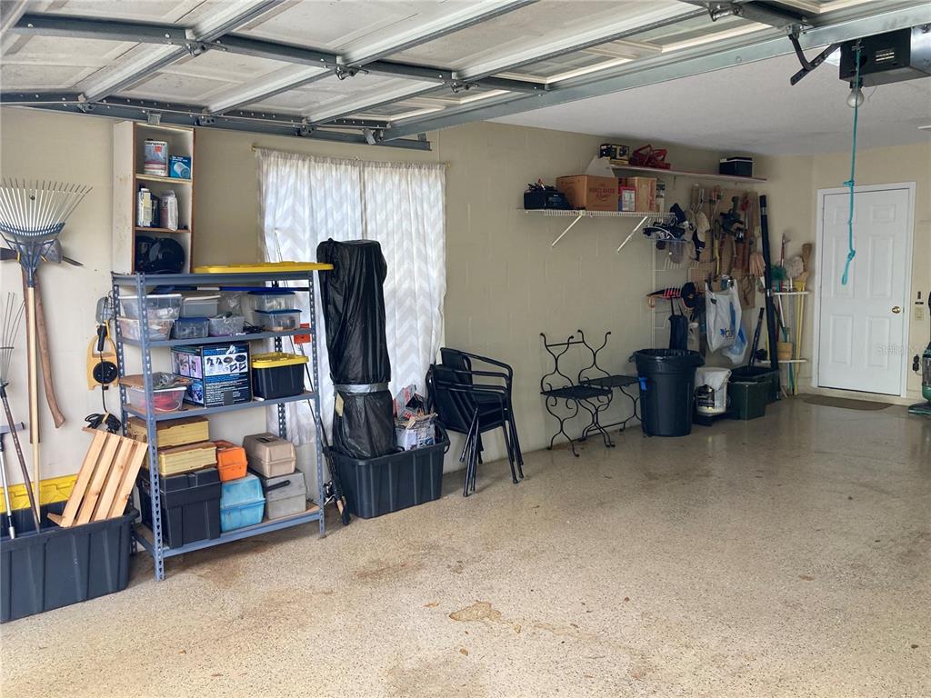 A garage with a metal storage rack, wall shelving, and various tools and equipment — 9029 PENELOPE DRIVE, WEEKI WACHEE, FL