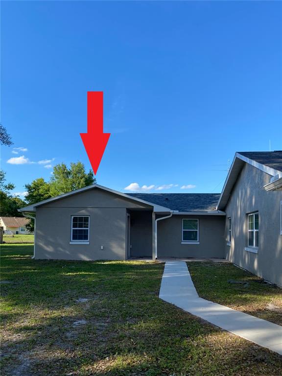 The exterior of a single-story house features a gray stucco finish and a gable roof — 2825 NICOLE AVENUE, KISSIMMEE, FL