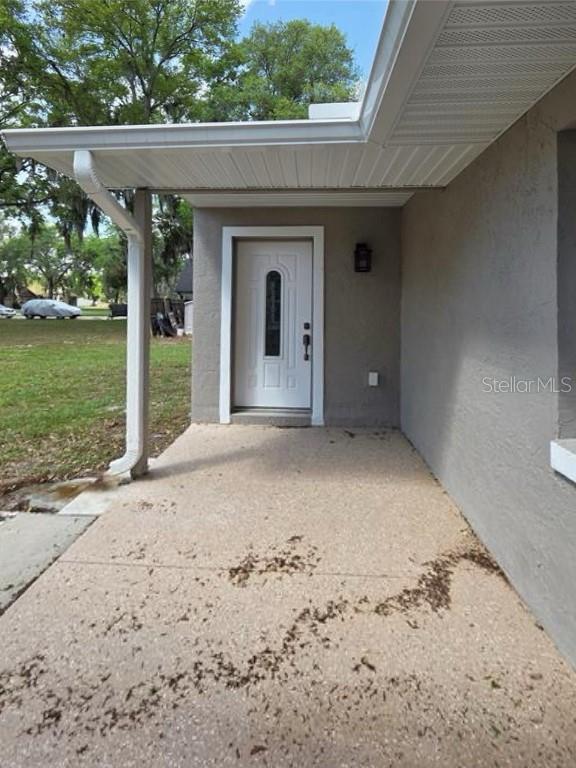 A covered concrete porch leads to a white front door on a gray stucco house — 2825 NICOLE AVENUE, KISSIMMEE, FL