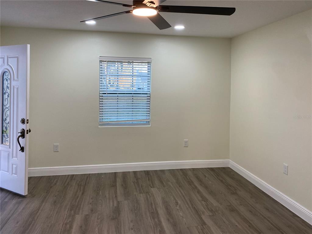 An empty room features light-colored walls, wood-look flooring, a ceiling fan, and a window — 2825 NICOLE AVENUE, KISSIMMEE, FL