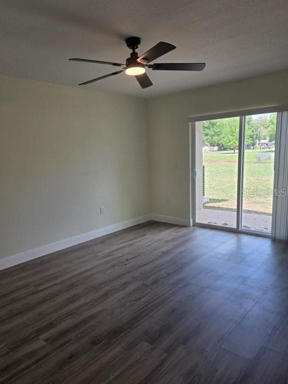 An empty room features wood-look flooring, a ceiling fan, and a sliding glass door — 2825 NICOLE AVENUE, KISSIMMEE, FL