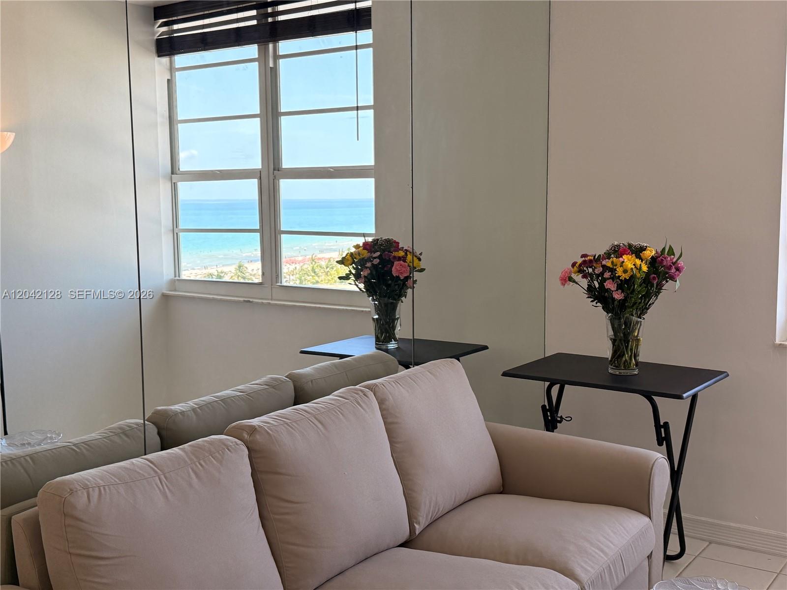 A living room features a beige sofa, mirrored walls, and a view of the ocean — 100 Lincoln Rd # 1025, Miami Beach FL 33139, MIAMI BEACH, FL
