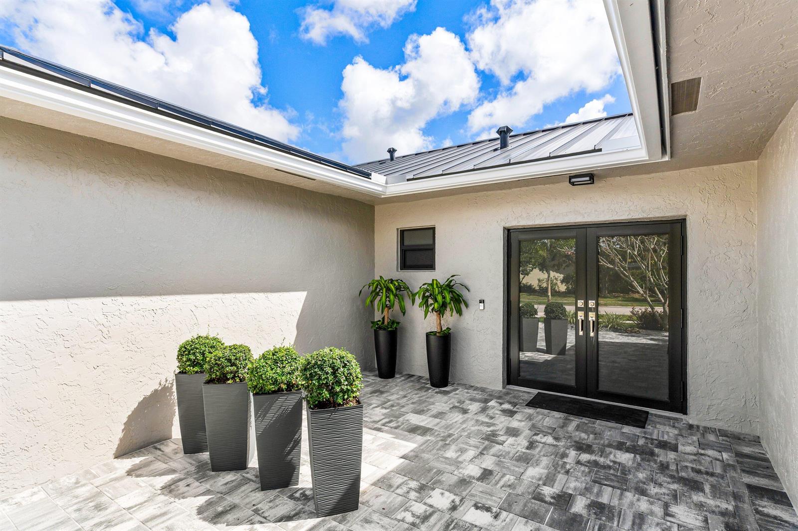 An outdoor courtyard features a paved floor, four small potted shrubs, and two tall plants — 21212 Escondido Way, Boca Raton FL 33433, BOCA RATON, FL