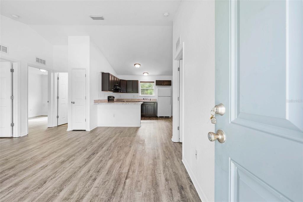 An open-concept kitchen with dark cabinets and light flooring is viewed from an entryway — 2549 W CASTANIA DRIVE, CITRUS SPRINGS, FL