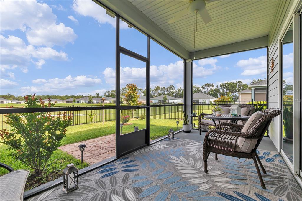 A screened-in porch features wicker furniture, a patterned rug, and views of a grassy yard — 7509 SW 78TH TERRACE, OCALA, FL