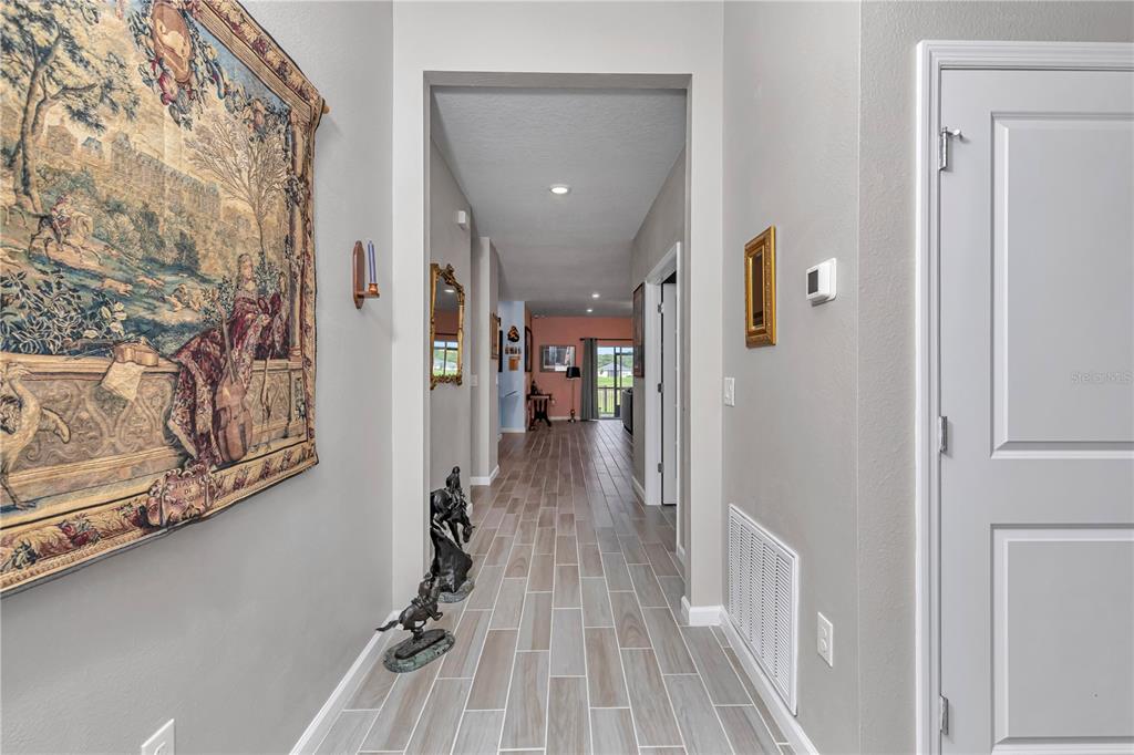 A hallway with light-colored tile flooring leads toward a living area with a sliding door — 7509 SW 78TH TERRACE, OCALA, FL