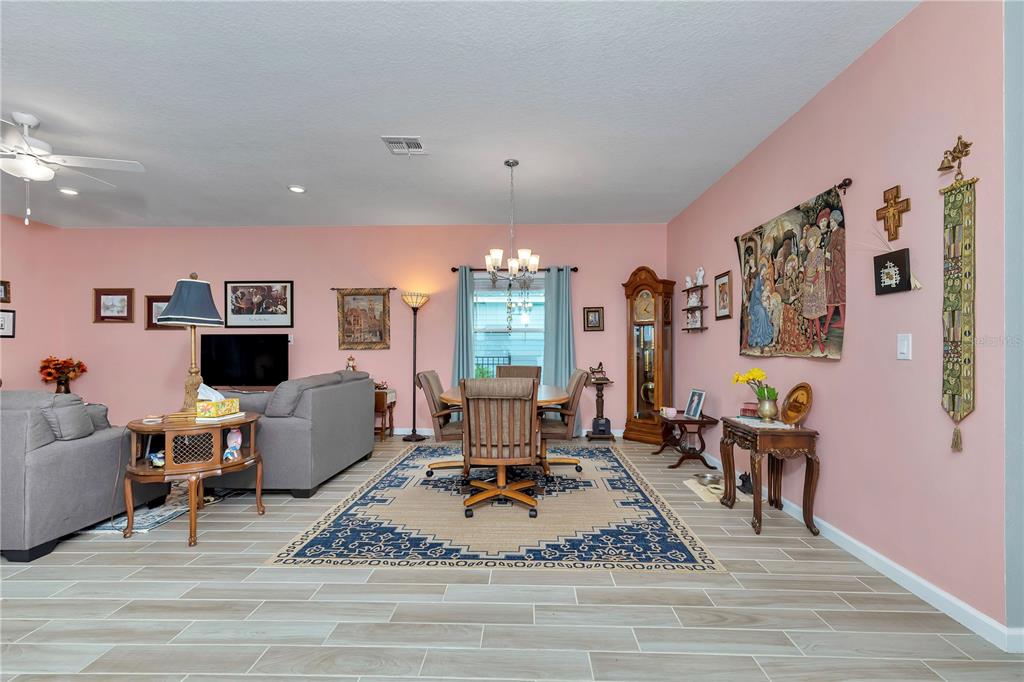 A living and dining area with pink walls, tile flooring, and a large area rug — 7509 SW 78TH TERRACE, OCALA, FL