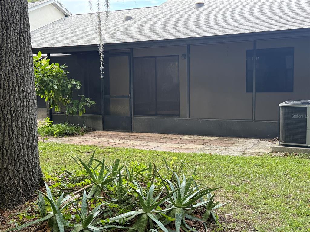A backyard view shows a screened-in patio with a paved floor and an air conditioning unit — 517 WHISPERING PINES BOULEVARD, INVERNESS, FL