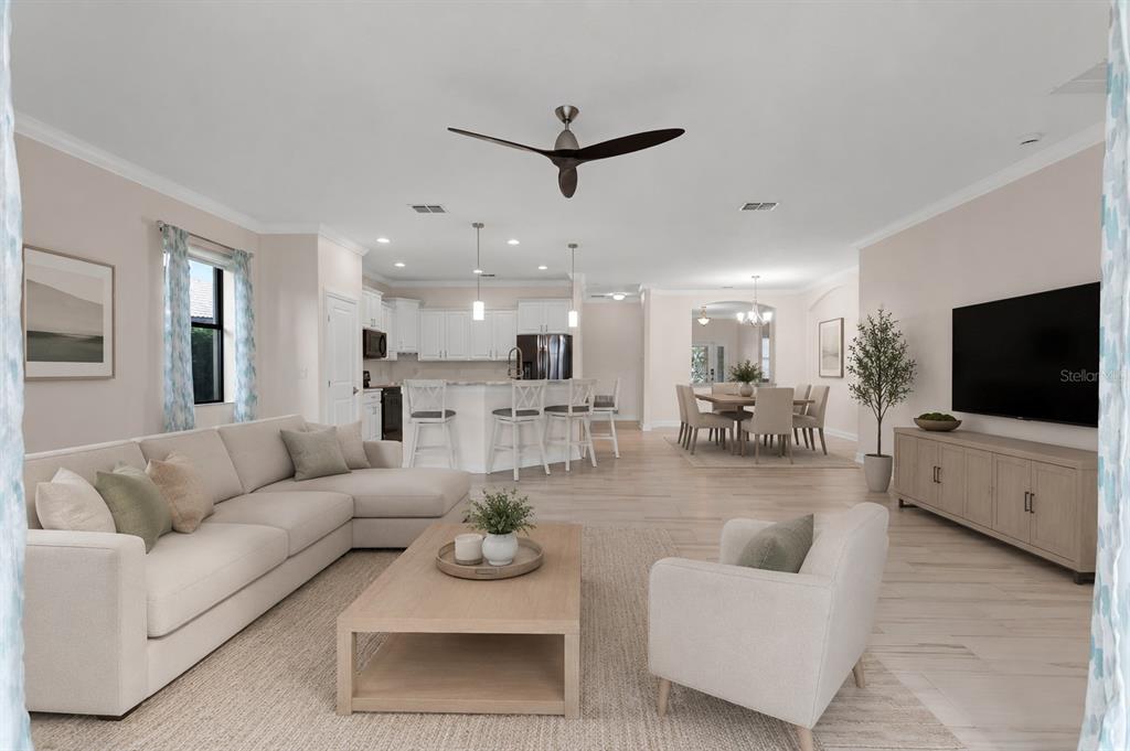 An open-concept living room and kitchen feature light wood floors, neutral furniture, and white cabinetry — 8972 DOVE VALLEY WAY, DAVENPORT, FL