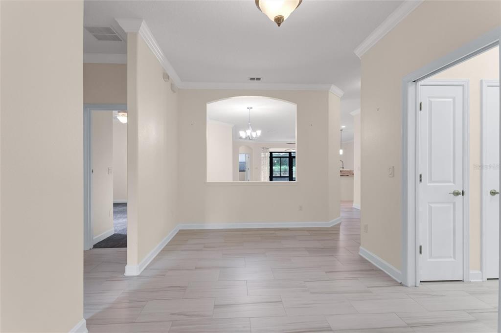 A bright, neutral-toned room features light wood-look tile flooring and a large arched wall cutout — 8972 DOVE VALLEY WAY, DAVENPORT, FL
