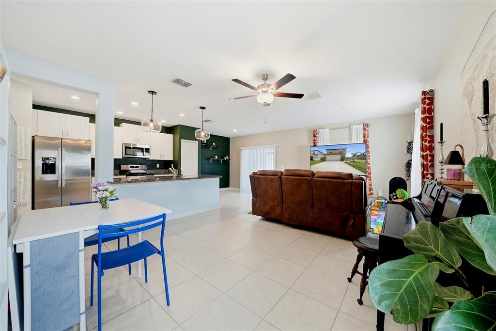 An open-concept living area features a kitchen with white cabinets, a brown sofa, and piano — 6298 BAR S BAR TRAIL, ZEPHYRHILLS, FL