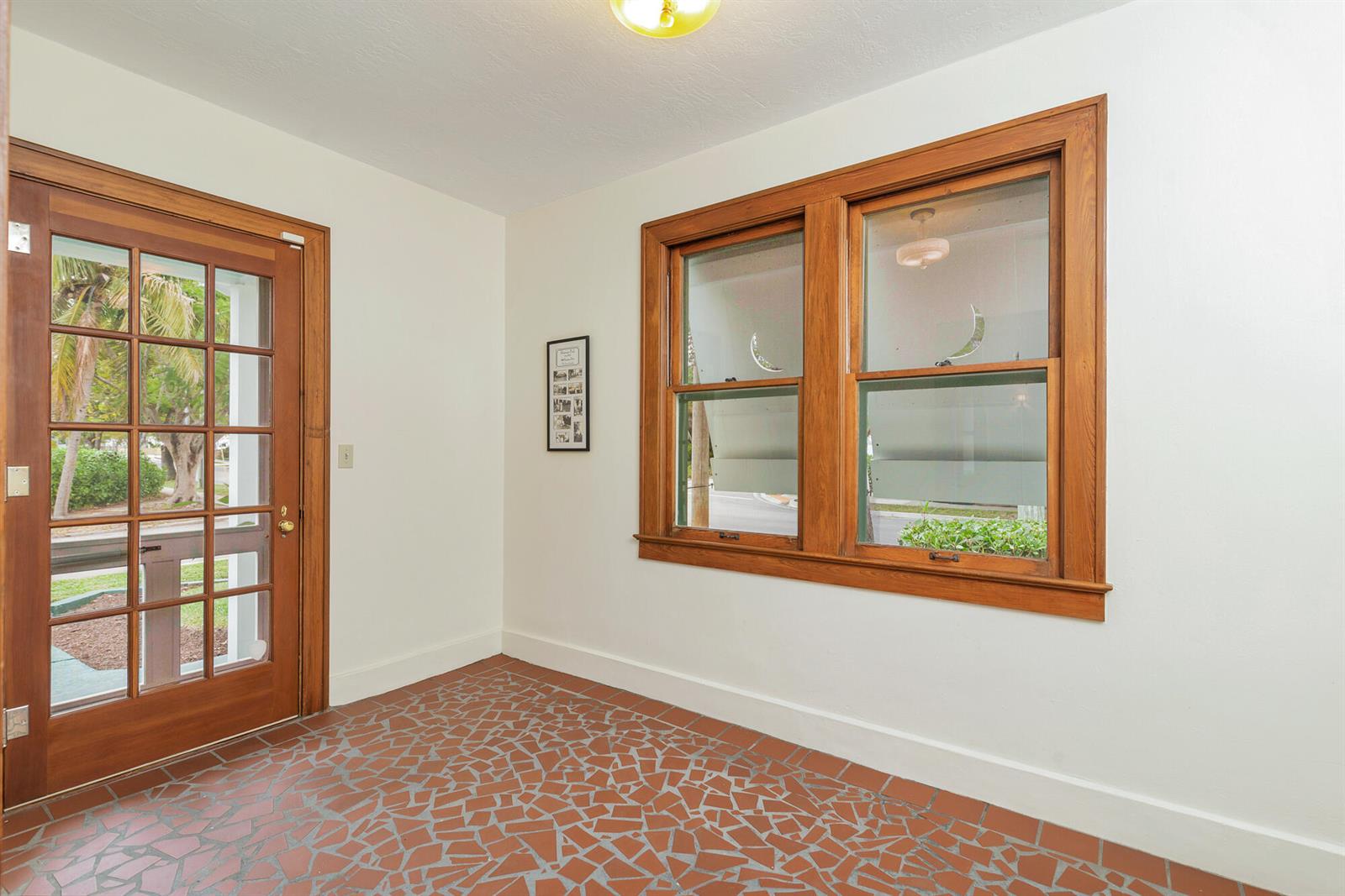 A sunroom features a mosaic tile floor, wood-trimmed windows, and a glass-paneled wooden door — 800 Kanuga Drive, West Palm Beach FL 33401, WEST PALM BEACH, FL
