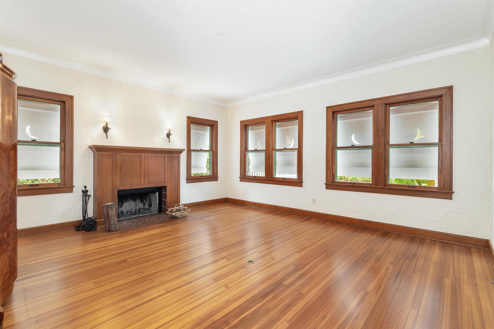 An empty living room features hardwood floors, a wood fireplace, and multiple windows with trim — 800 Kanuga Drive, West Palm Beach FL 33401, WEST PALM BEACH, FL