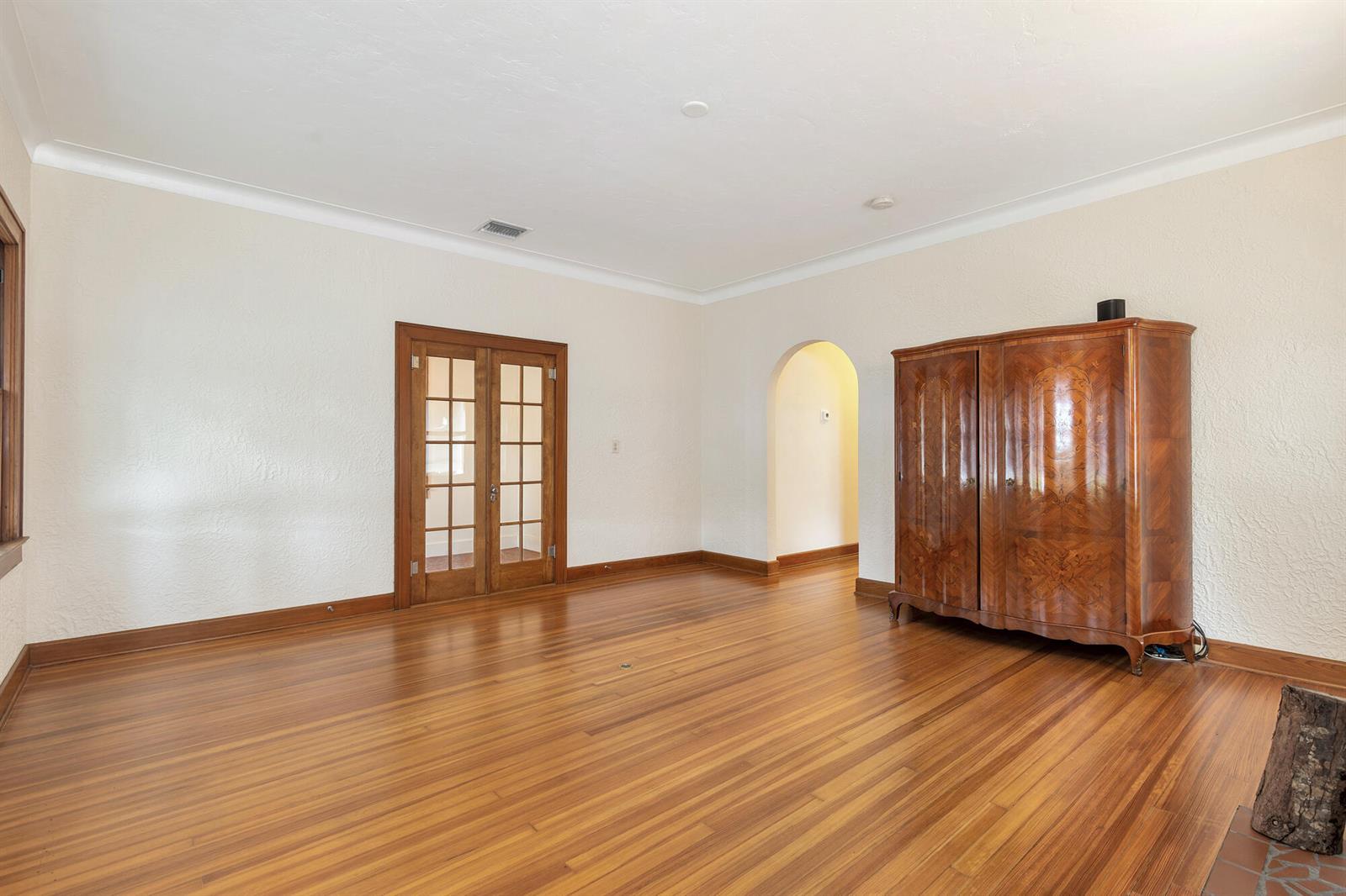 A room with hardwood floors, a wooden armoire, French doors, and an arched doorway — 800 Kanuga Drive, West Palm Beach FL 33401, WEST PALM BEACH, FL
