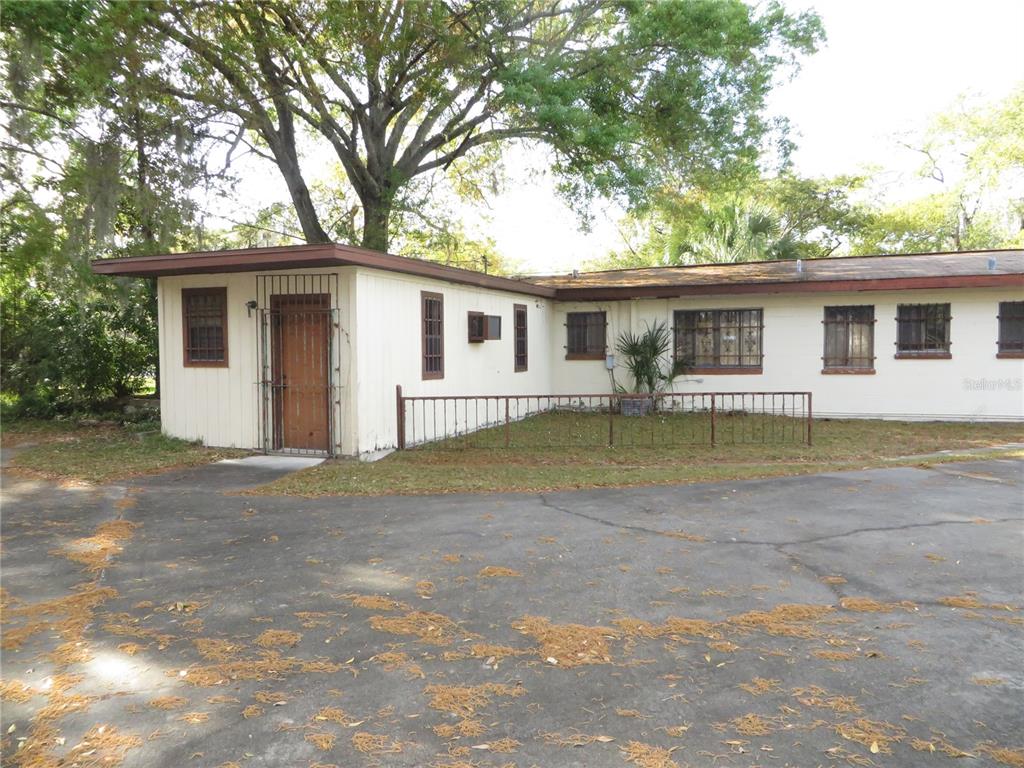 A single-story building with light-colored siding, a flat roof, and metal security bars on windows — 420 W CHERRY STREET, KISSIMMEE, FL