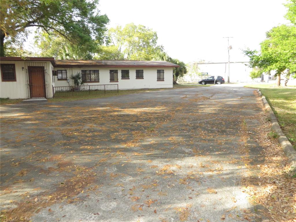 A single-story building with a large paved parking lot covered in fallen leaves — 420 W CHERRY STREET, KISSIMMEE, FL