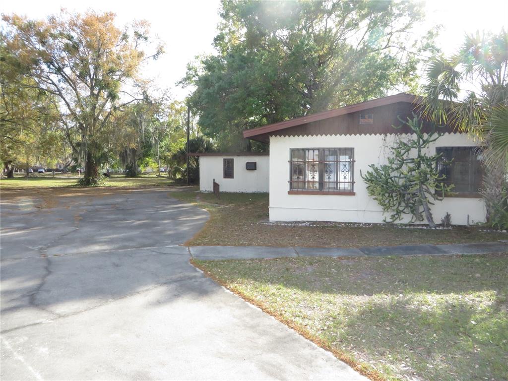 A single-story building with a white exterior and brown trim sits beside a paved driveway — 420 W CHERRY STREET, KISSIMMEE, FL