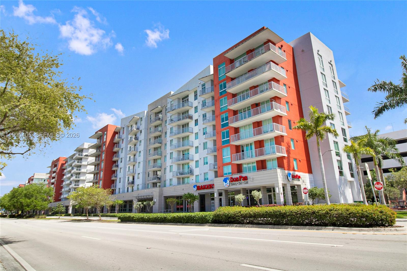 A multi-story apartment building with a ground-floor bakery and street-level landscaping under a blue sky — 7661 NW 107th Ave # 501, Doral FL 33178, DORAL, FL