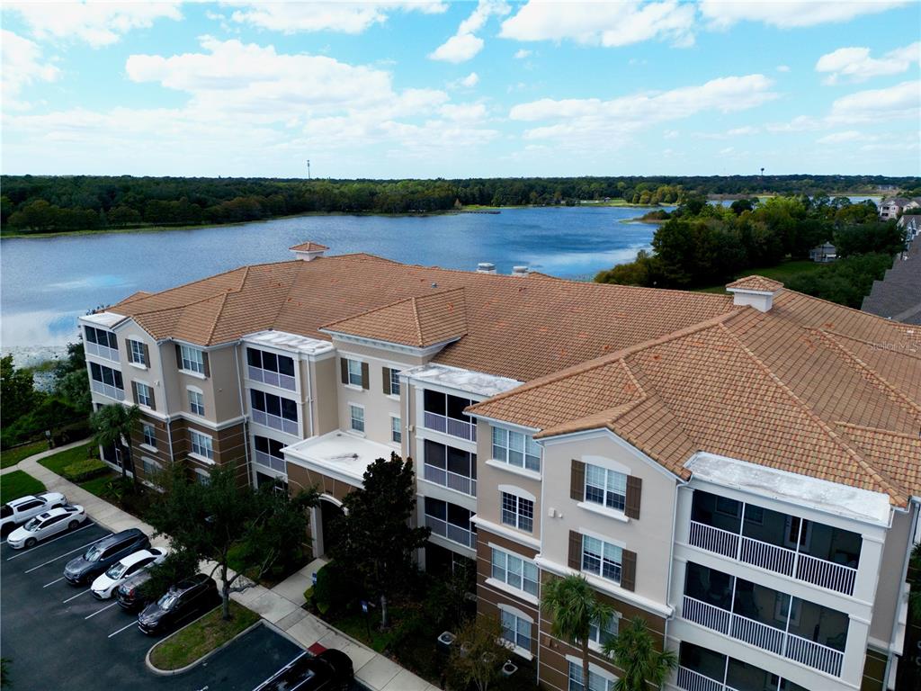 An aerial view of a multi-story apartment building with a tiled roof near a lake — 3356 ROBERT TRENT JONES DRIVE UNIT 407, ORLANDO, FL