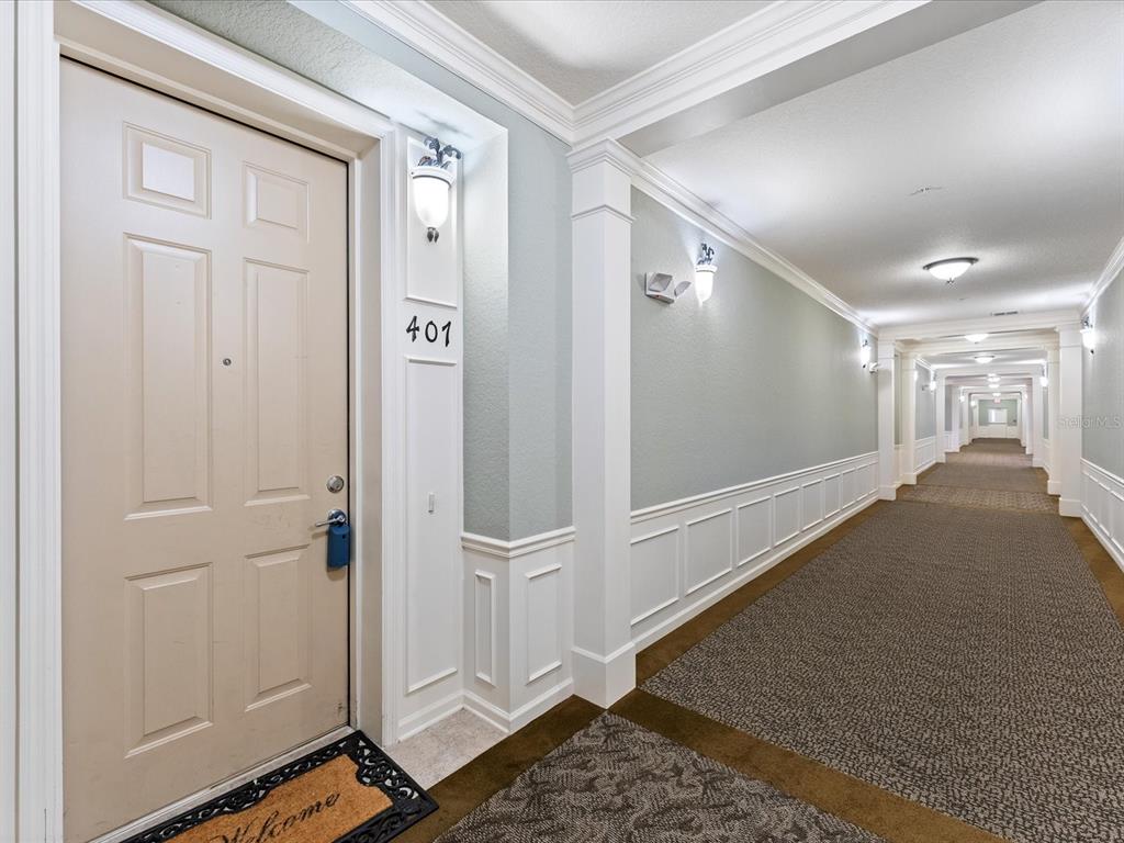 A beige apartment door labeled 401 opens into a long, carpeted hallway with white wainscoting — 3356 ROBERT TRENT JONES DRIVE UNIT 407, ORLANDO, FL